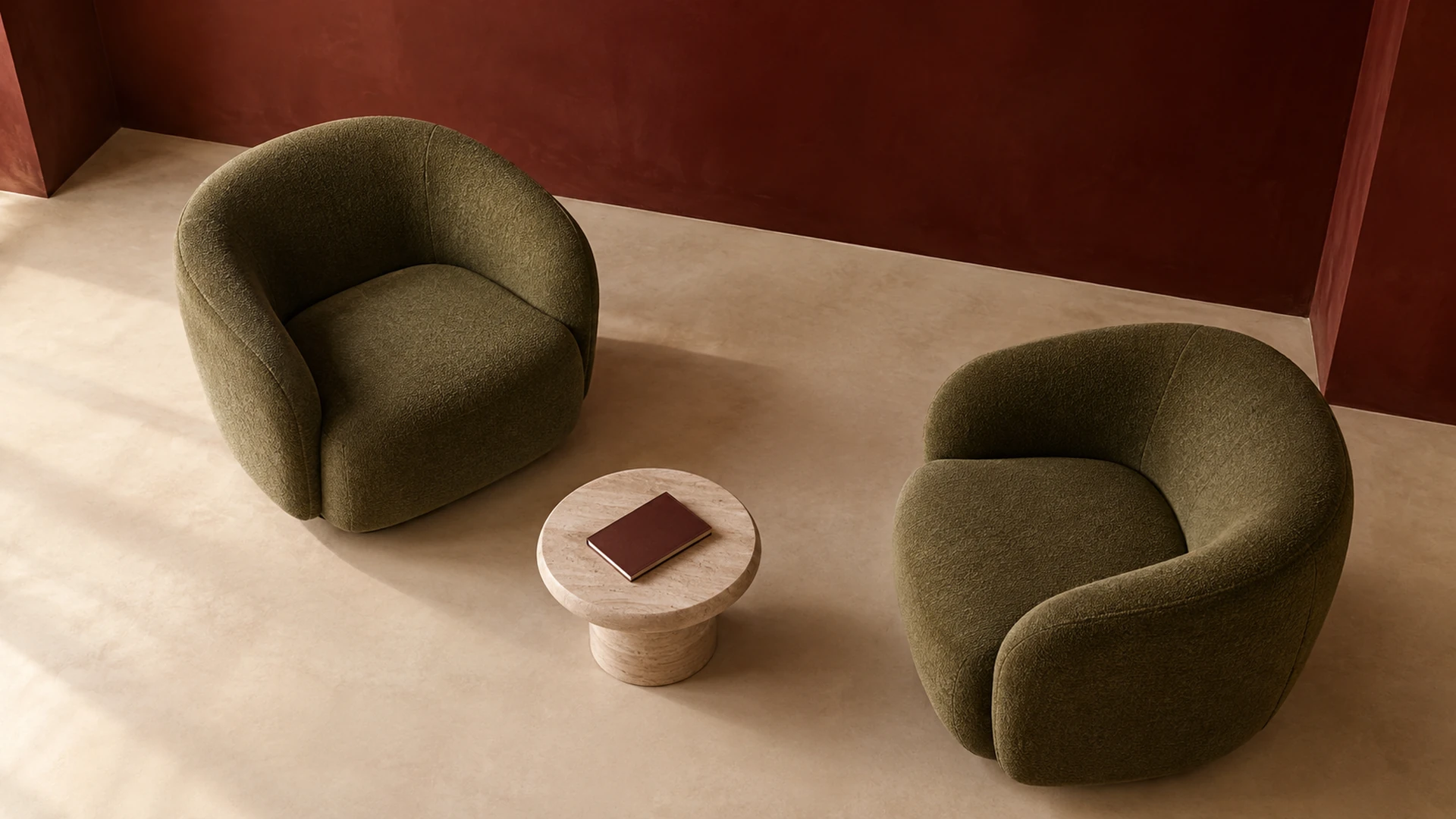 Two sage chairs and an open space for an ongoing conversation, with a notebook on a small champagne table.